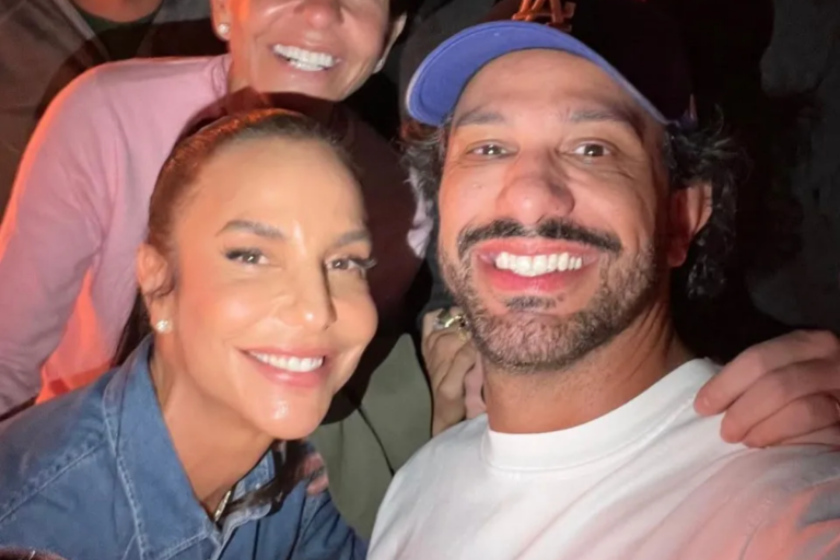 Ivete Sangalo sorri ao lado do empresário Tiago Maia em selfie aproximada. Ela usa camisa jeans e ele veste camiseta branca e boné azul.