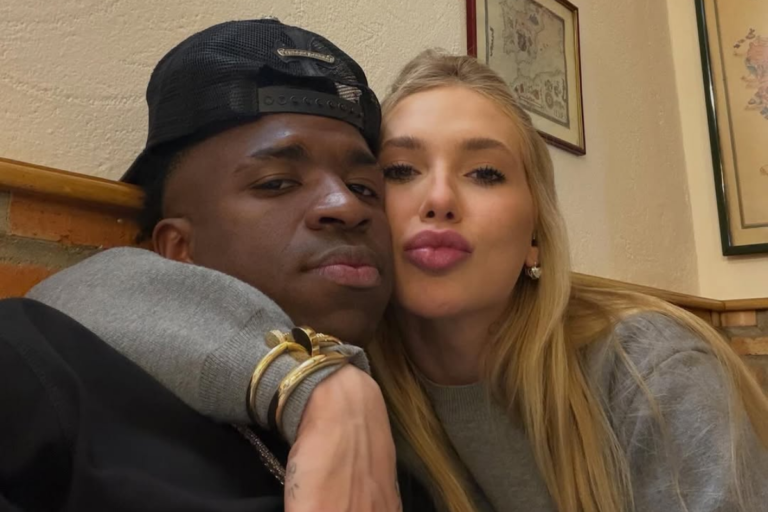 Vini Jr e Virginia Fonseca posam juntos; o jogador usa um boné preto virado para trás e Virginia, de cabelos loiros, faz bico para a foto enquanto o abraça.