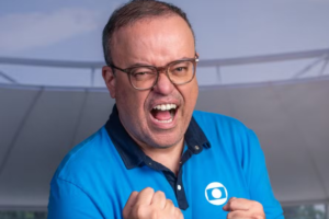 NEveraldo Marques, vestindo camisa polo azul com o logo da Globo, com expressão de euforia e punhos cerrados.