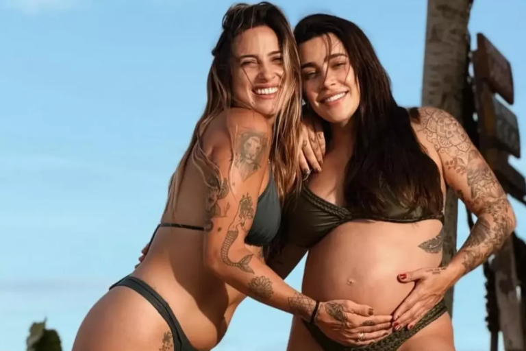 Tati Dias e a cantora grávida Lauana Prado abraçadas e sorrindo durante dia de sol na praia.