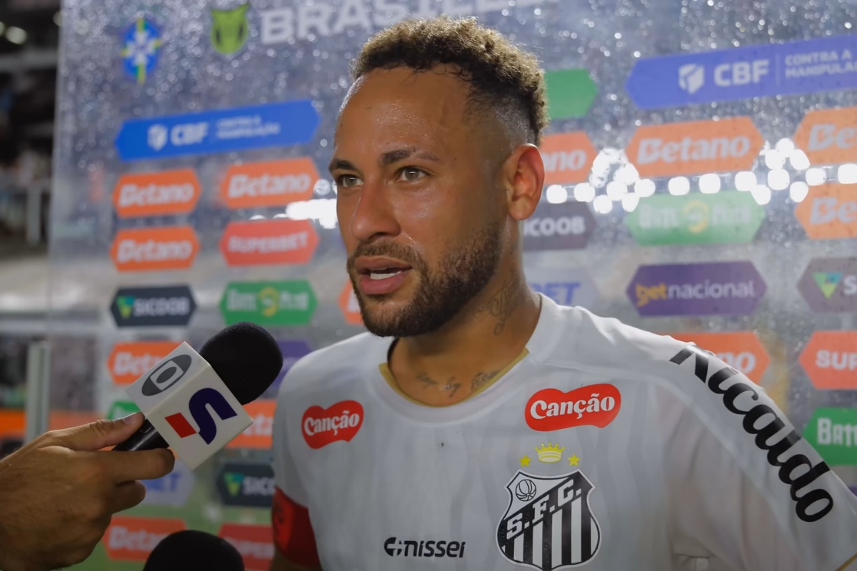 Neymar falando ao microfone da TV Globo durante entrevista na beira do gramado vestindo a camisa branca do Santos FC.