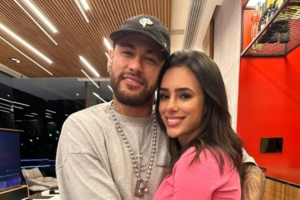 Neymar e Bruna Biancardi abraçados e sorrindo para a câmera em um ambiente interno.