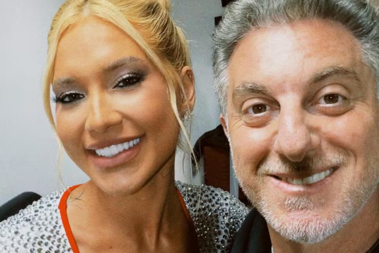 Virginia Fonseca e Luciano Huck sorridentes posando juntos para uma selfie em estúdio de gravação.