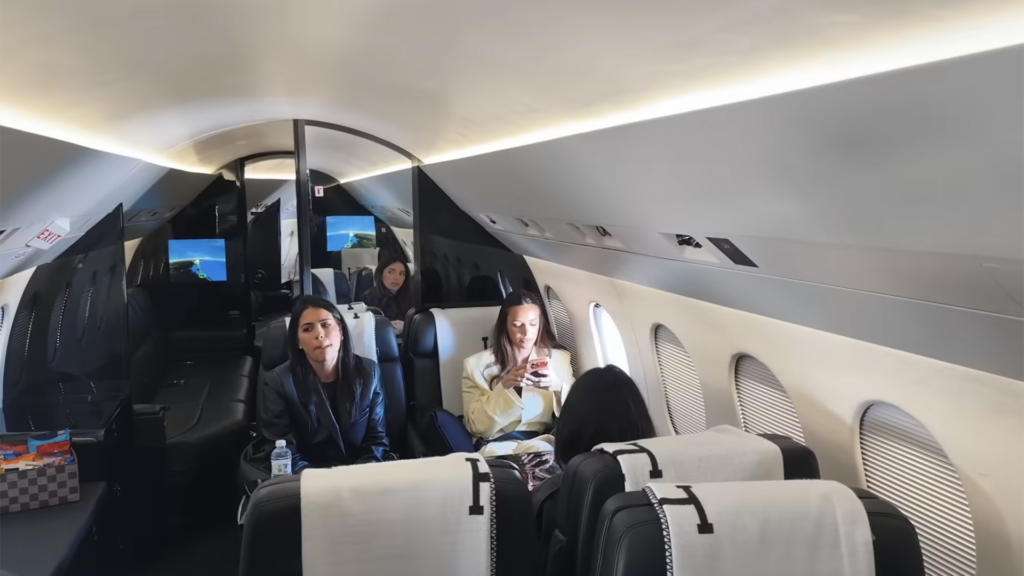 Interior luxuoso do jato particular de Neymar com poltronas de couro preto, mesas individuais, telas de entretenimento e acabamento refinado.