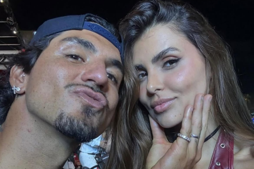 Gabriel Medina fazendo biquinho e Isabella Arantes apoiando o rosto com a mão, exibindo anel de compromisso em selfie próxima.