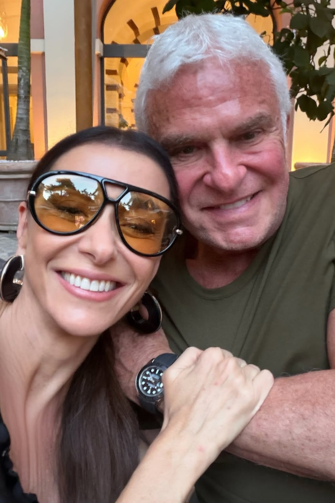 Mônica Martelli e Fernando Altério sorrindo e posando juntos para uma selfie em ambiente externo com iluminação quente.