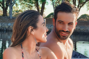Wanessa Camargo e Bruno Bevan sorridentes, em momento de lazer ao ar livre próximo a uma área de água.