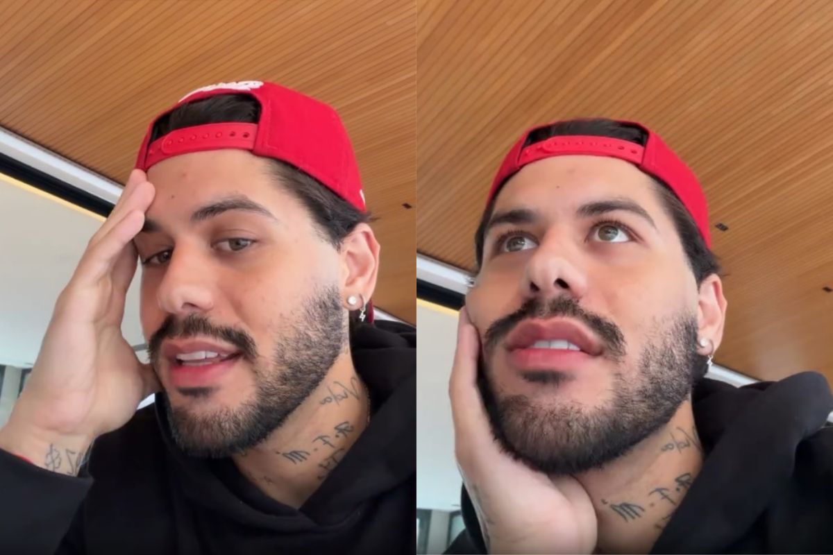 Zé Felipe usando boné vermelho e blusa preta, com tatuagens no pescoço e mão, em close-up.