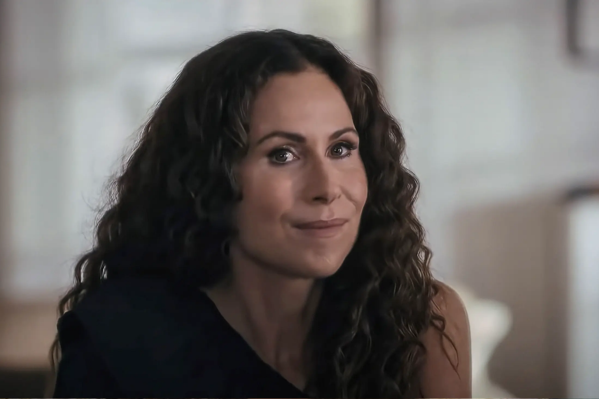 Atriz Minnie Driver com longos cabelos castanhos cacheados e expressão sorridente em plano médio